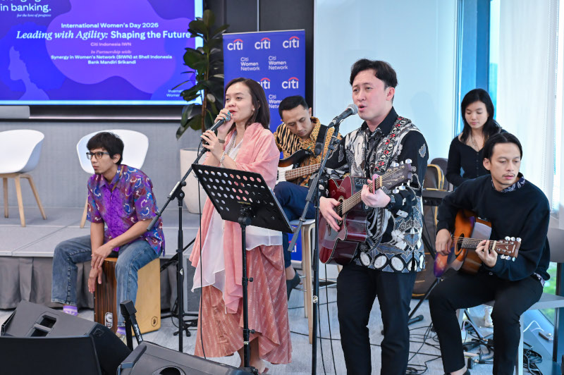 Danu singing and playing guitar on stage with a band